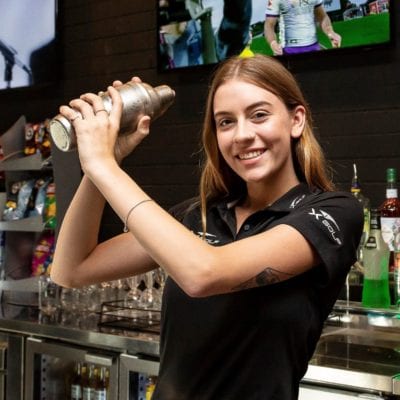 Girl standing in bar shaking a cocktails
