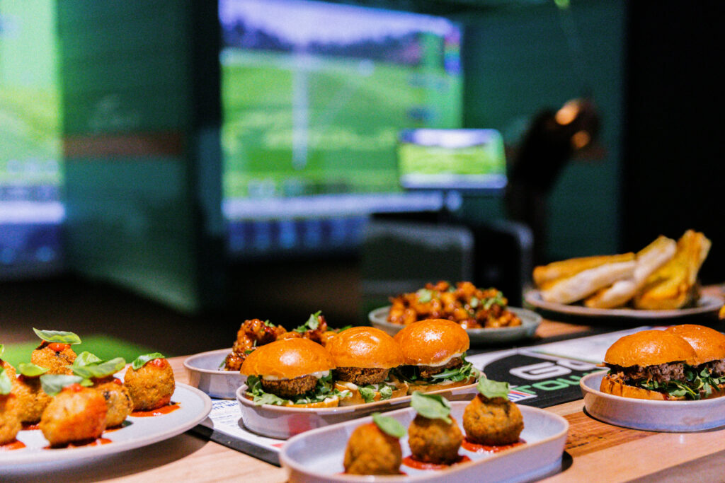 Burgers and share plates served at X-Golf with simulator screens behind
