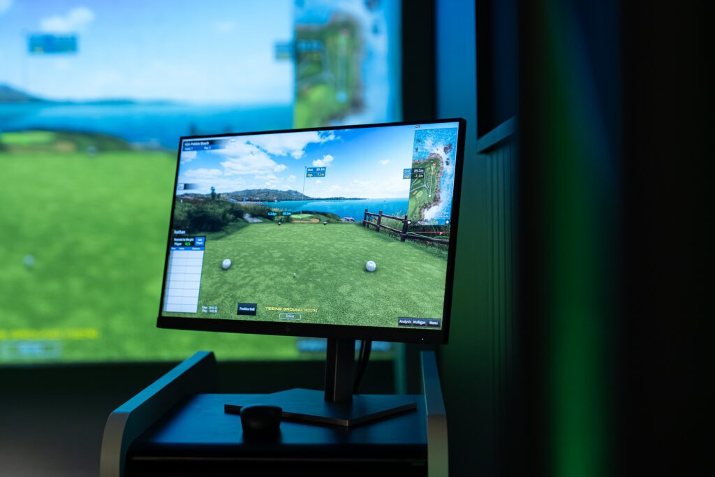X-Golf simulator with monitor displaying virtual golf course during kids gameplay