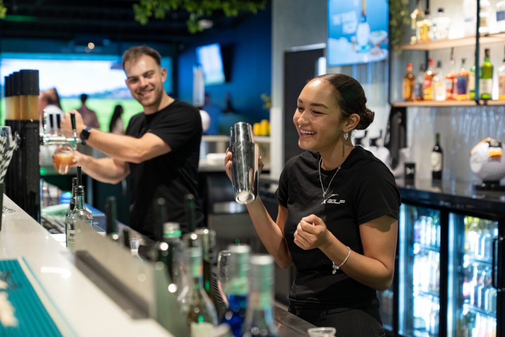 Staff mixing drinks behind bar at X-Golf Morley