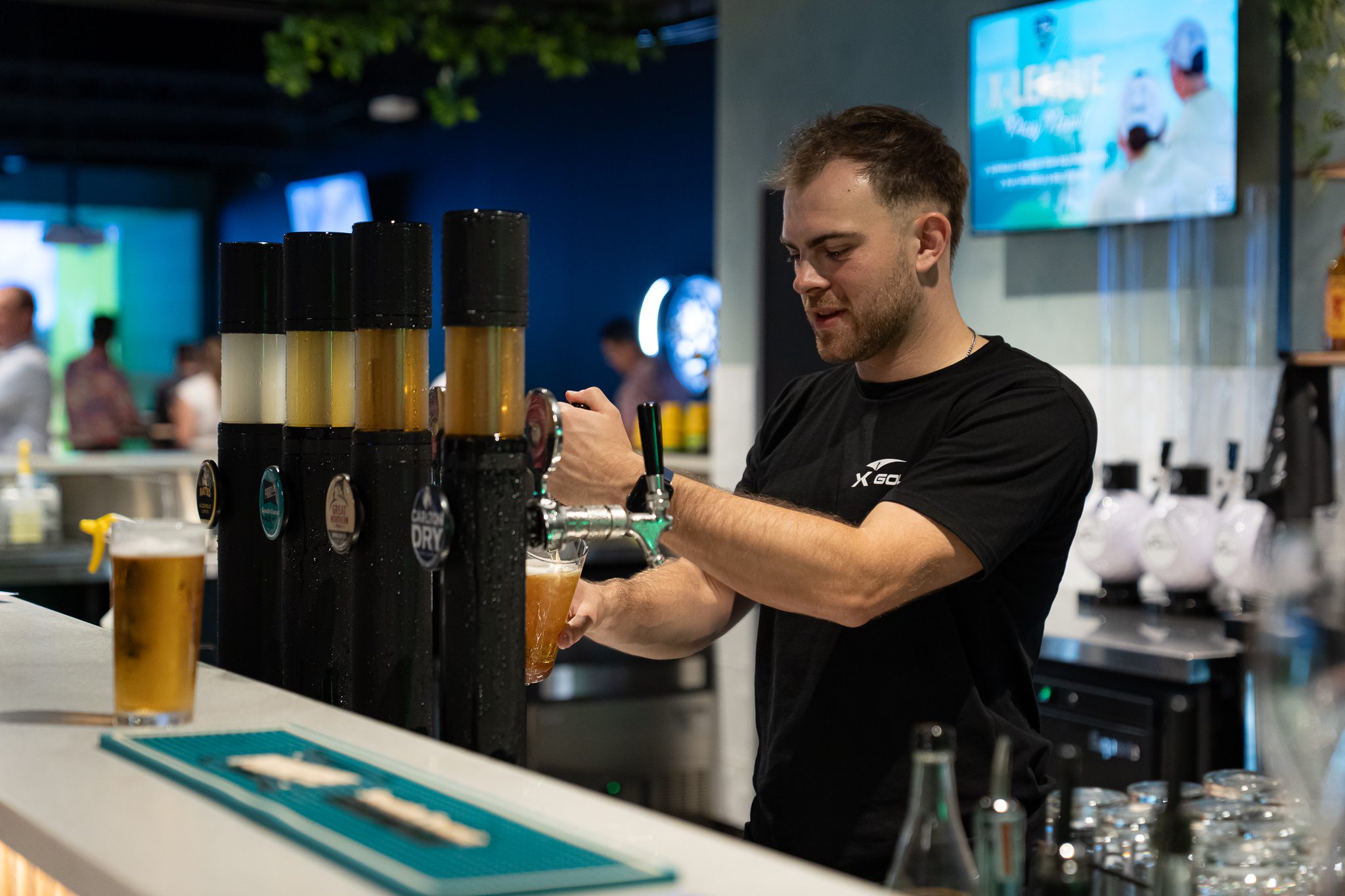 Bartender pouring beer at X-Golf Morley venue bar