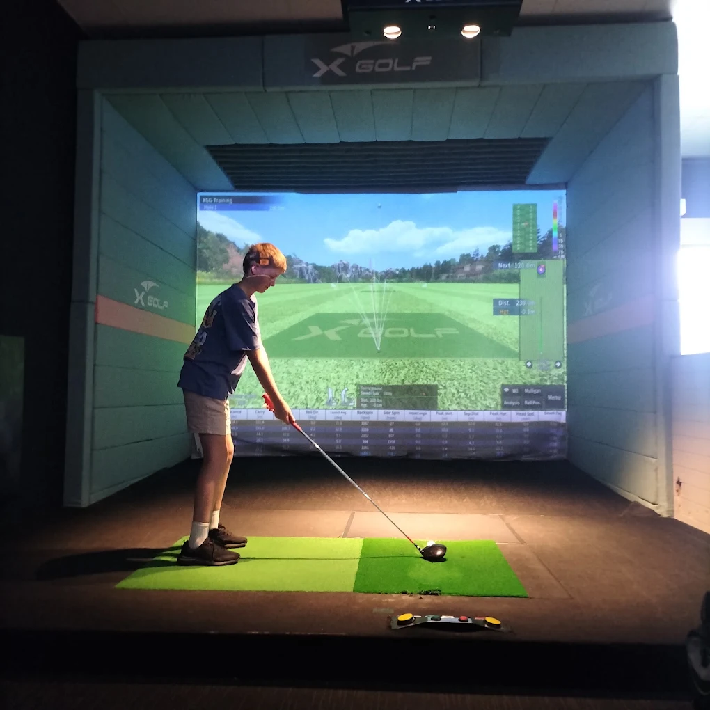 Kid preparing a shot on X-Golf Mornington indoor golf simulator