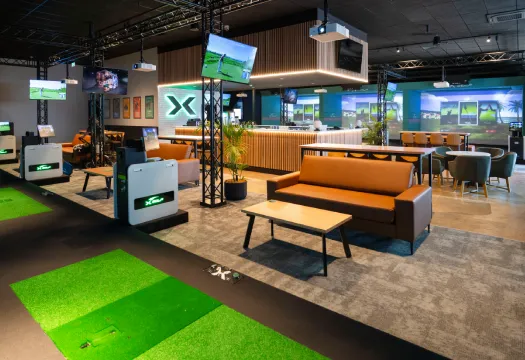 Interior lounge seating and golf simulator bays at X-Golf Fyshwick in Canberra, ACT.