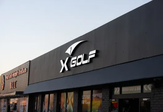 Exterior storefront signage of an X-Golf venue representing a new territory coming soon.