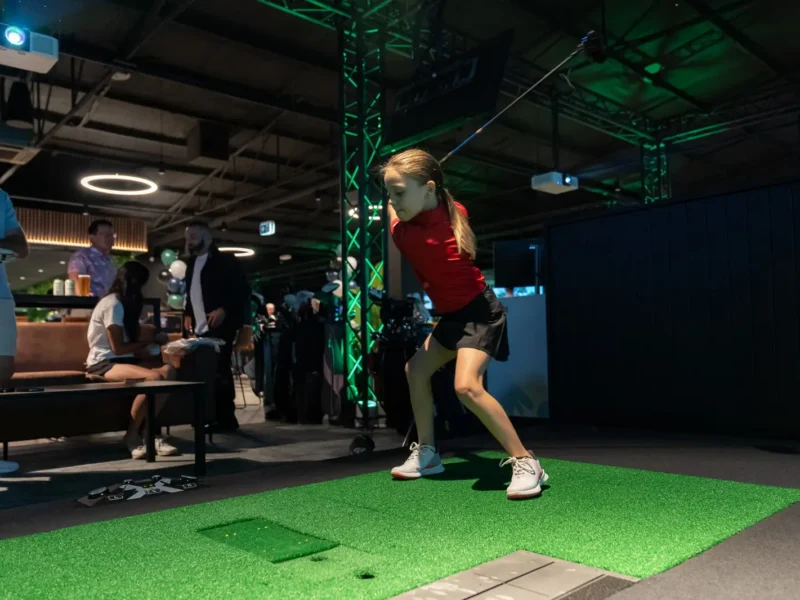 Child taking a swing on an X-Golf indoor golf simulator