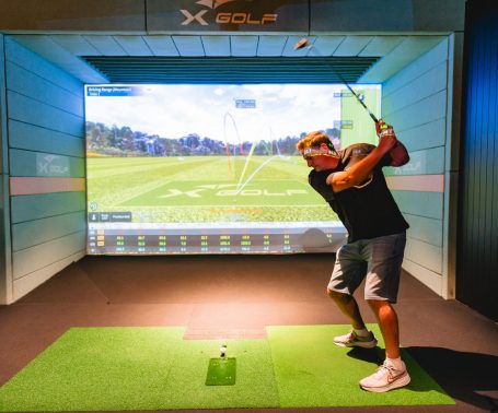 Golfer practicing swing inside X-Golf Surrey Hills simulator bay