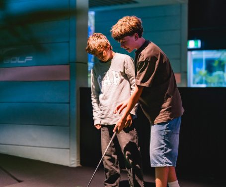 Two juniors learning golf swing at X-Golf Surrey Hills