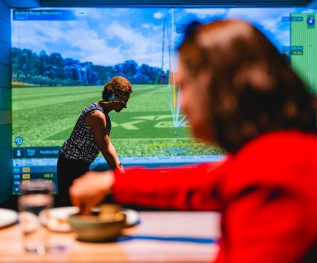 Guest enjoying simulator golf while dining at X-Golf Surrey Hills
